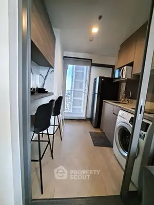 Modern kitchen with sleek appliances and stylish bar seating in a contemporary apartment.