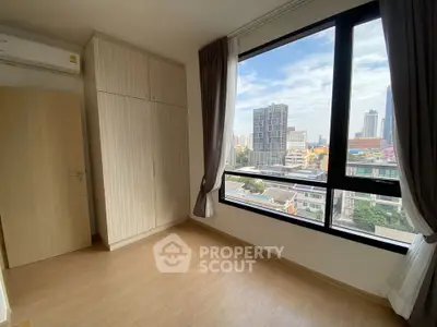 Bright bedroom with large window offering stunning city view in modern apartment.
