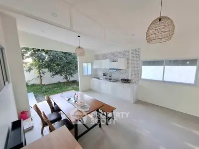 Spacious open-layout kitchen with dining area and garden view, featuring modern design and ample natural light.