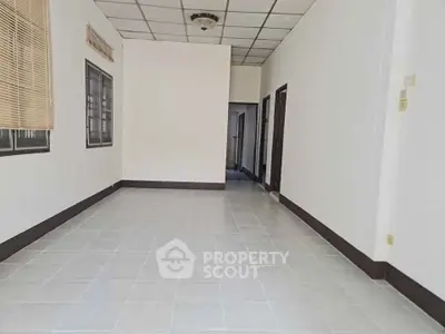 Spacious empty room with tiled flooring and neutral walls, ready for customization.