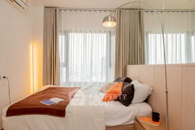 Cozy modern bedroom with floor lamp and large windows offering natural light.