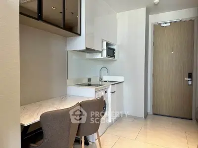 Modern compact kitchen with integrated appliances and cozy dining area in a stylish apartment.