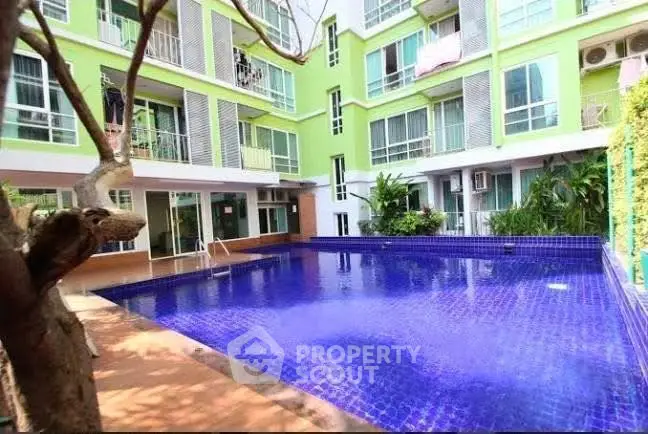 Modern apartment building with vibrant pool and lush greenery