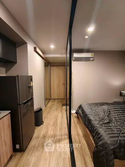 Modern bedroom with sleek design, featuring wooden flooring and a compact kitchen area.