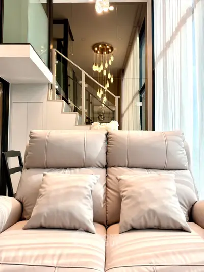 Luxurious modern living room with elegant staircase and plush leather sofa, perfect for stylish urban living.