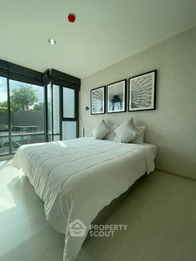 Modern bedroom with large windows and stylish decor in a bright, airy apartment.