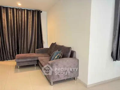 Modern living room with sleek gray sofa and elegant curtains
