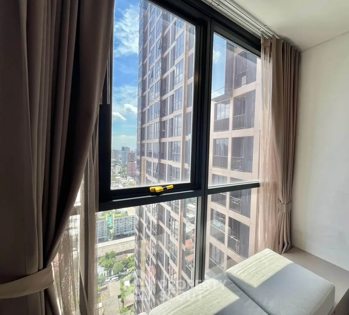 Stunning high-rise apartment view with floor-to-ceiling windows and cityscape backdrop.