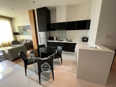 Modern open-layout kitchen and living room with sleek black cabinetry and stylish dining area.