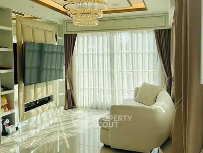 Luxurious living room with elegant chandelier and large TV, featuring floor-to-ceiling windows and plush sofa.