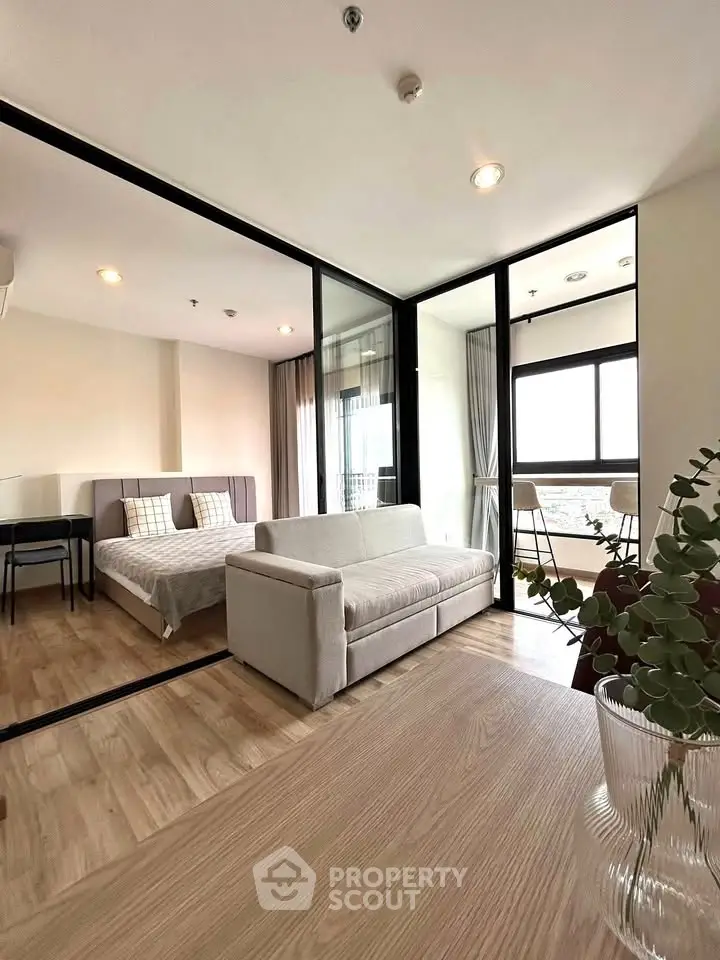 Modern studio apartment with glass partition, cozy living area, and natural light.