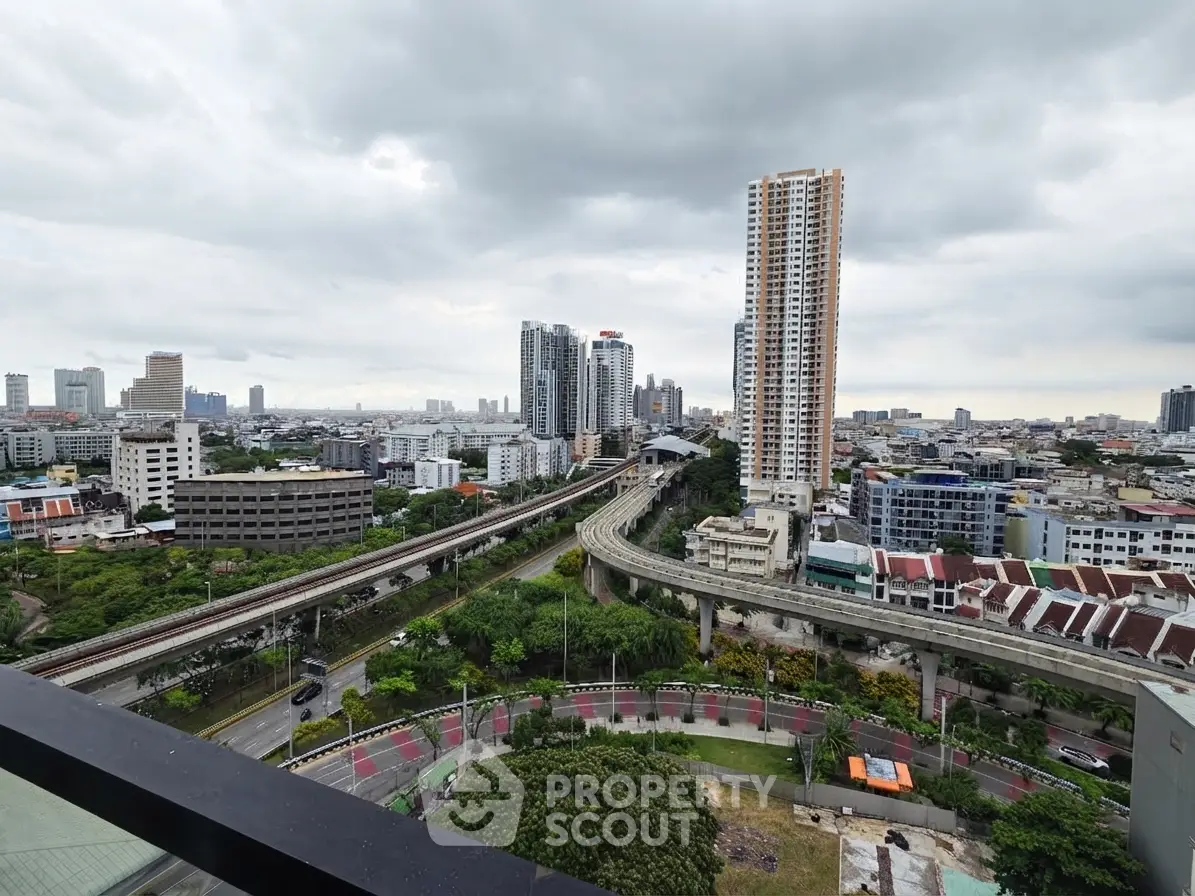Stunning cityscape view from high-rise balcony overlooking urban skyline and transportation lines.