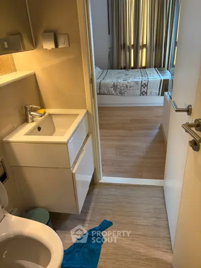 Compact bathroom with modern fixtures leading to a cozy bedroom with natural light.
