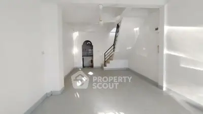 Spacious open-plan living area with staircase and ceiling fan, perfect for modern living.