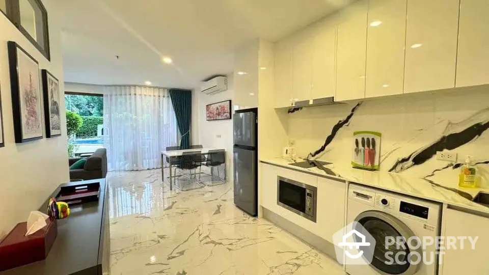 Modern kitchen with marble flooring, sleek appliances, and open layout leading to dining area.