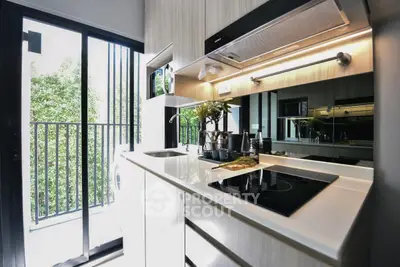 Modern kitchen with sleek design and balcony view, featuring induction stove and ample storage.