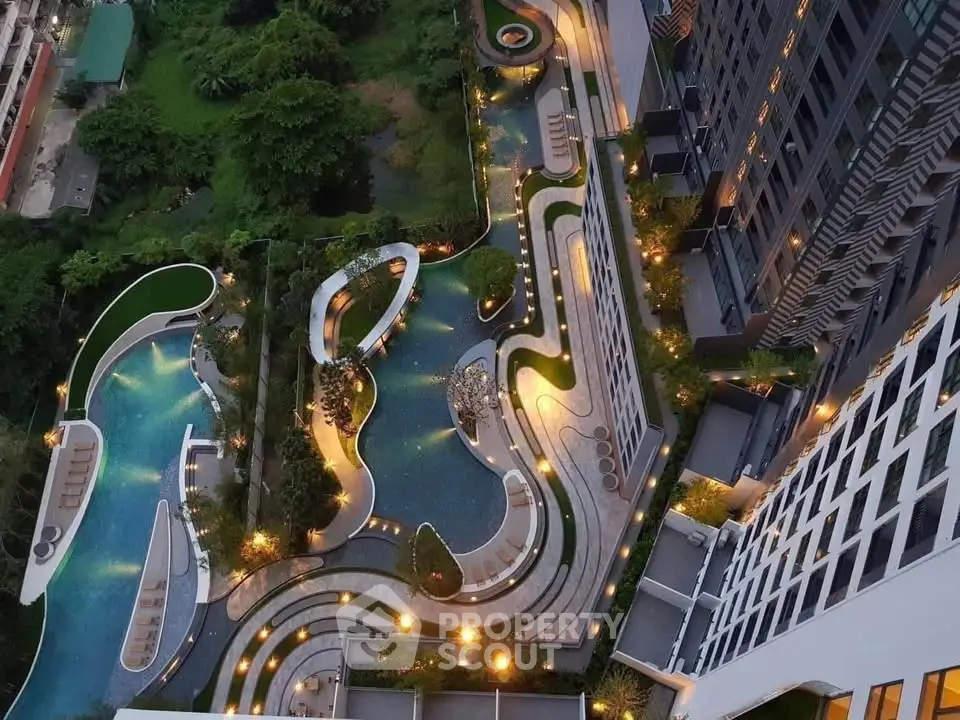 Stunning aerial view of luxury apartment complex with illuminated pool and landscaped gardens.
