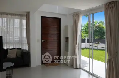Bright living room with sliding glass doors opening to a lush garden, featuring modern decor and natural light.