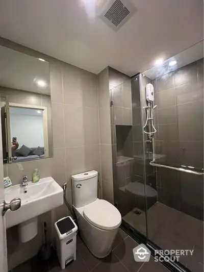 Modern bathroom with glass shower and sleek fixtures in contemporary apartment.