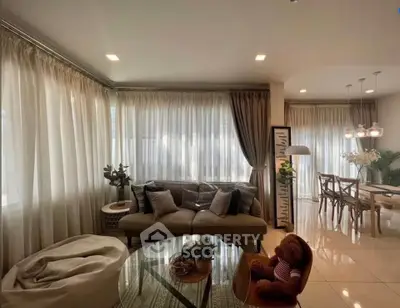 Spacious living room with elegant decor and dining area, featuring large windows and cozy seating.
