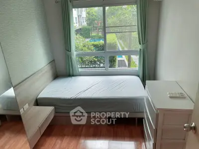 Cozy bedroom with large window overlooking lush garden and pool, featuring modern furniture and wooden flooring.