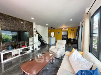 Spacious living room with modern decor and open kitchen layout, featuring large windows and stylish furnishings.