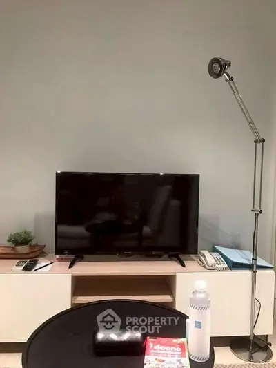 Modern living room with sleek TV setup and stylish floor lamp.