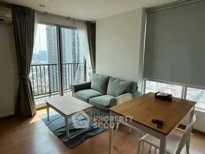 Modern living room with large windows and city view, featuring cozy sofa and dining area.