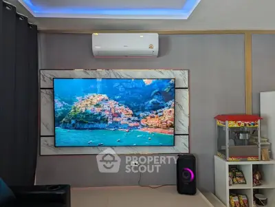 Modern living room with large TV, air conditioning, and snack corner for entertainment.