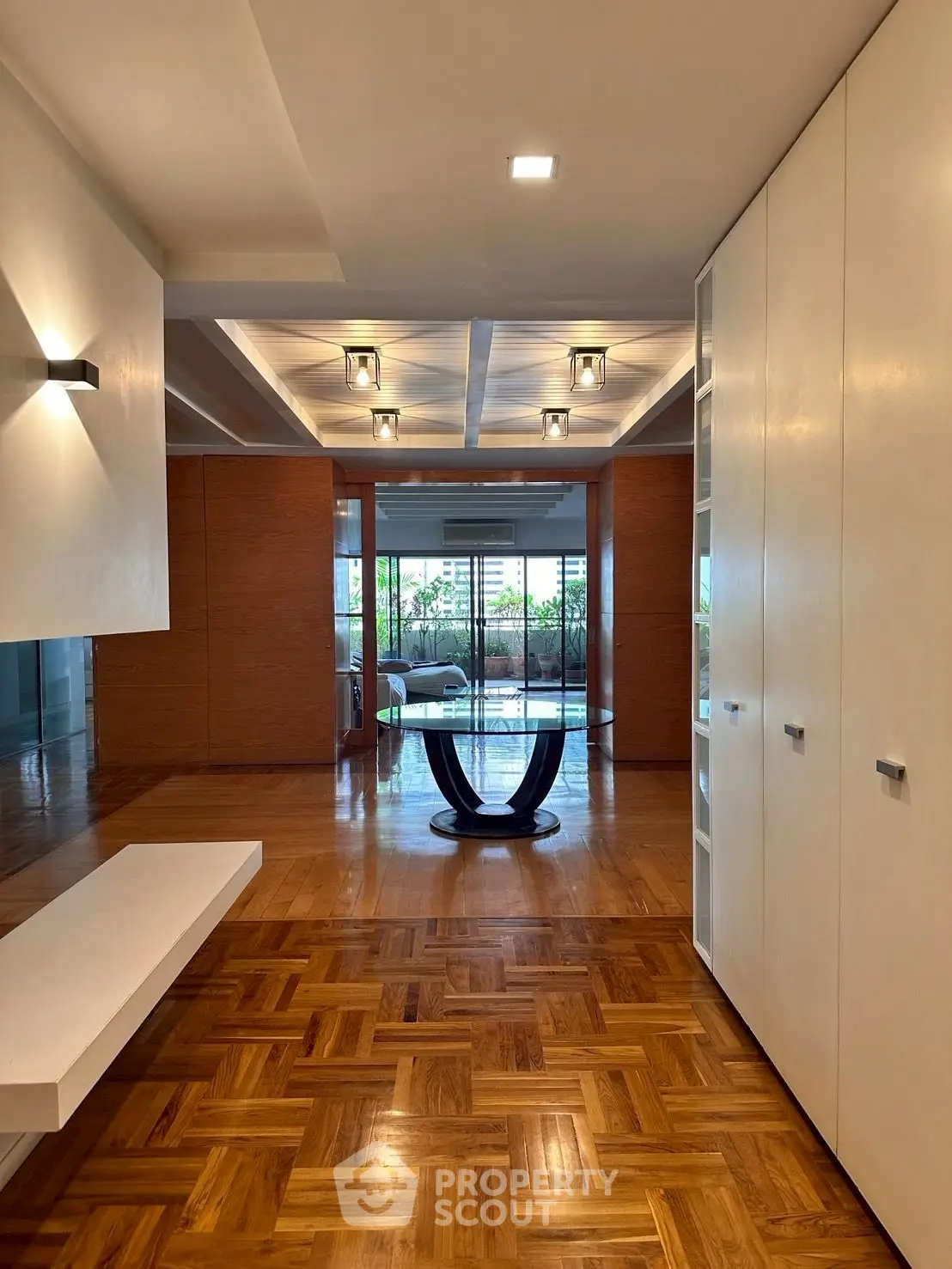 Spacious modern living area with elegant parquet flooring and stylish ceiling lights.