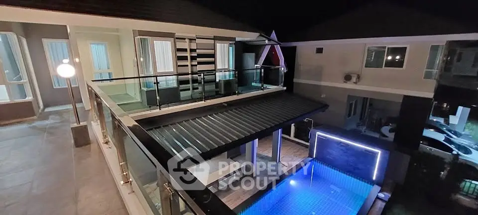 Luxurious modern home with illuminated pool and stylish balcony at night.