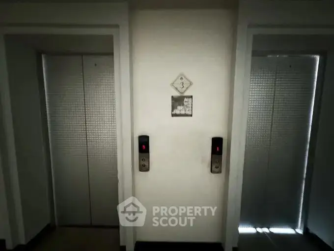 Modern building elevator lobby with two sleek elevator doors on the third floor.