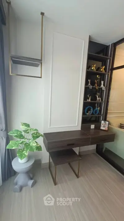 Modern study room with sleek desk, shelving, and decorative plant in stylish apartment.