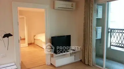 Cozy living room with TV and air conditioning, leading to a bedroom and balcony.