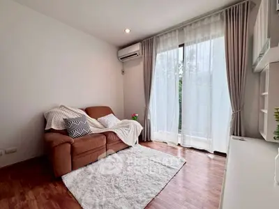 Cozy living room with plush sofa, wooden flooring, and large window for natural light.