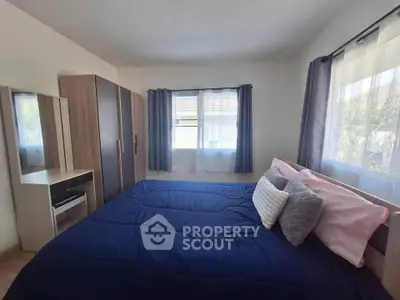 Cozy bedroom with stylish decor and ample natural light, featuring a comfortable bed and modern wardrobe.