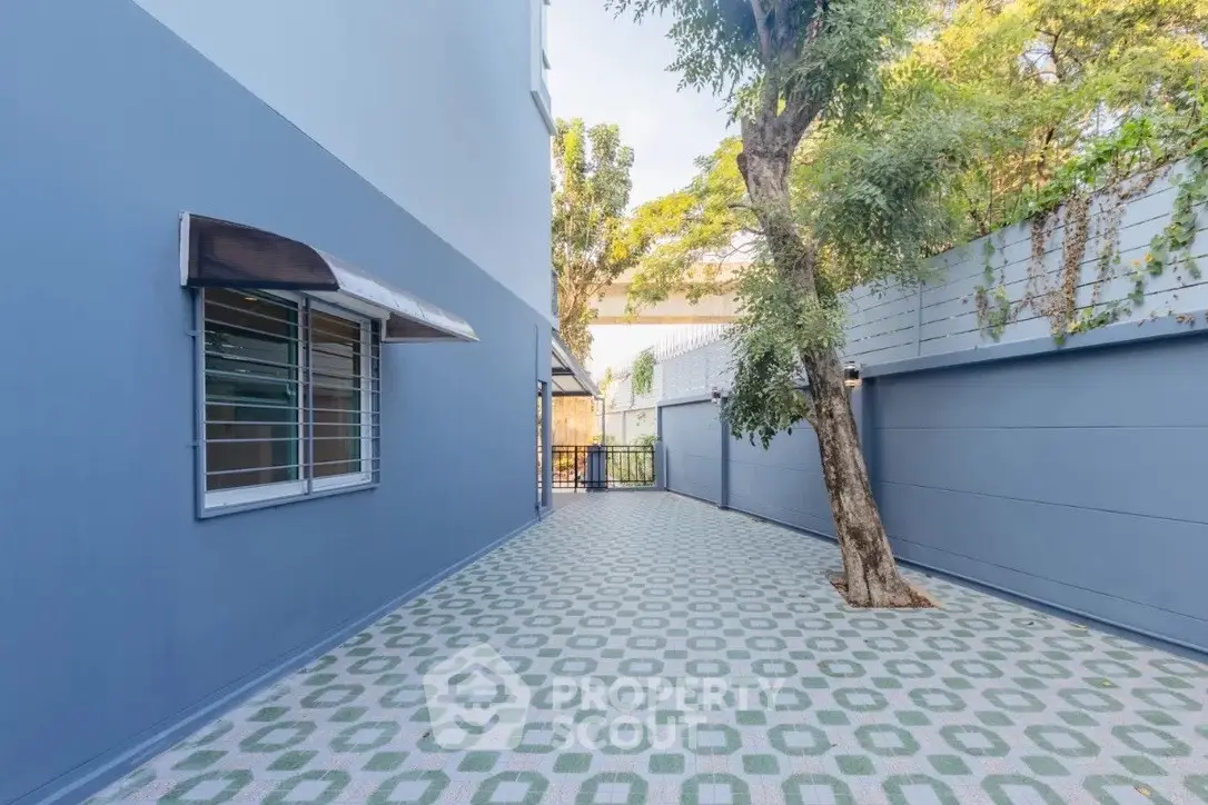 Spacious outdoor area with patterned flooring and tree, perfect for relaxation and gatherings.