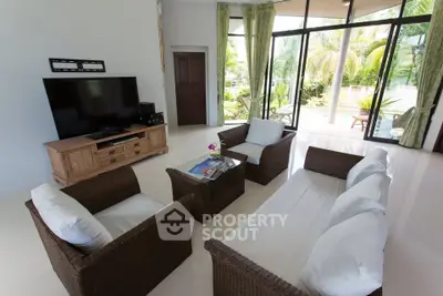 Spacious living room with modern wicker furniture and large glass doors to garden.