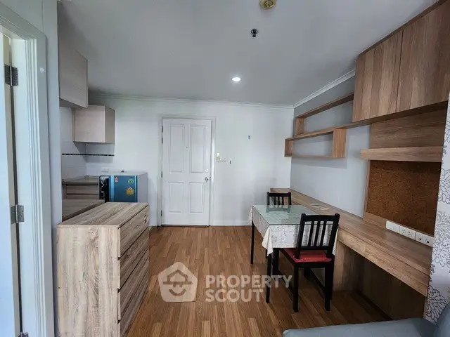 Cozy apartment interior with wooden flooring, compact kitchen, and dining area.