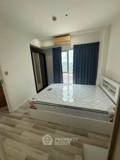 Modern bedroom with large window and air conditioning, featuring a new mattress and stylish flooring.