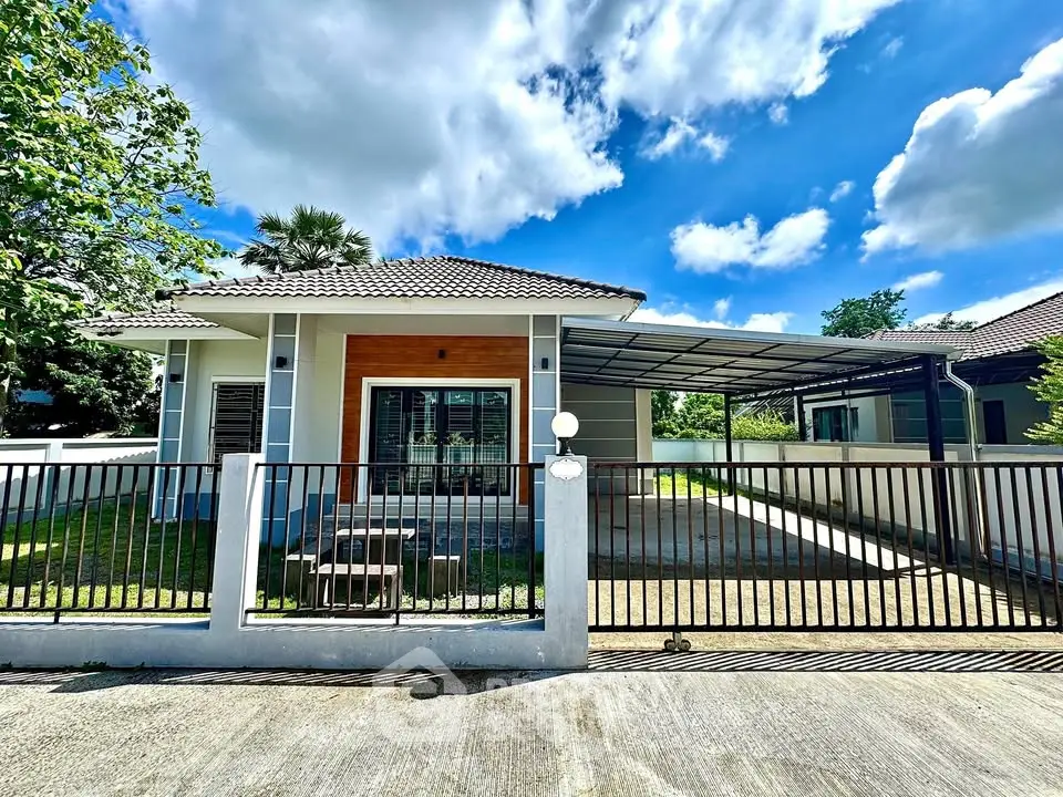 Charming single-story house with spacious driveway and lush garden under a clear blue sky.