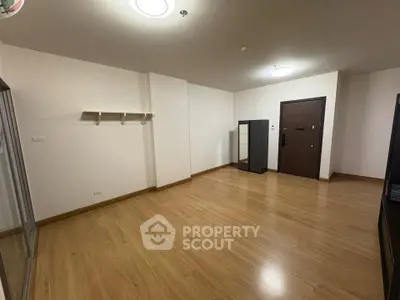 Spacious empty room with wooden flooring and modern door, ideal for customization.