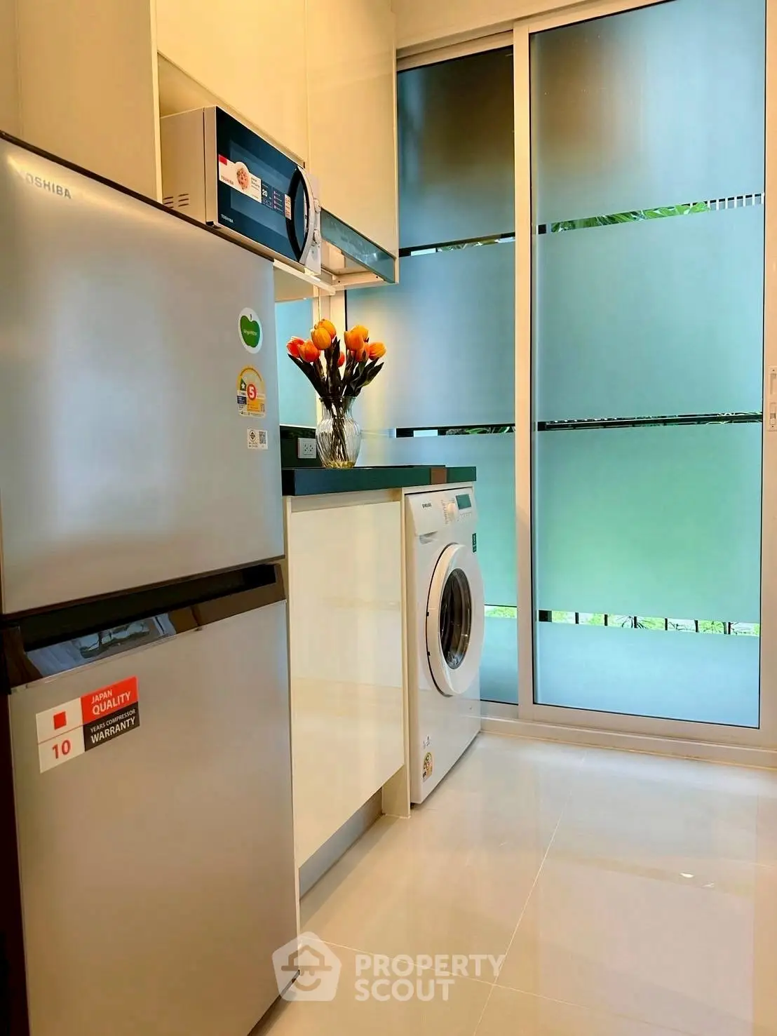 Modern kitchen with sleek appliances and washing machine in a bright, stylish interior.