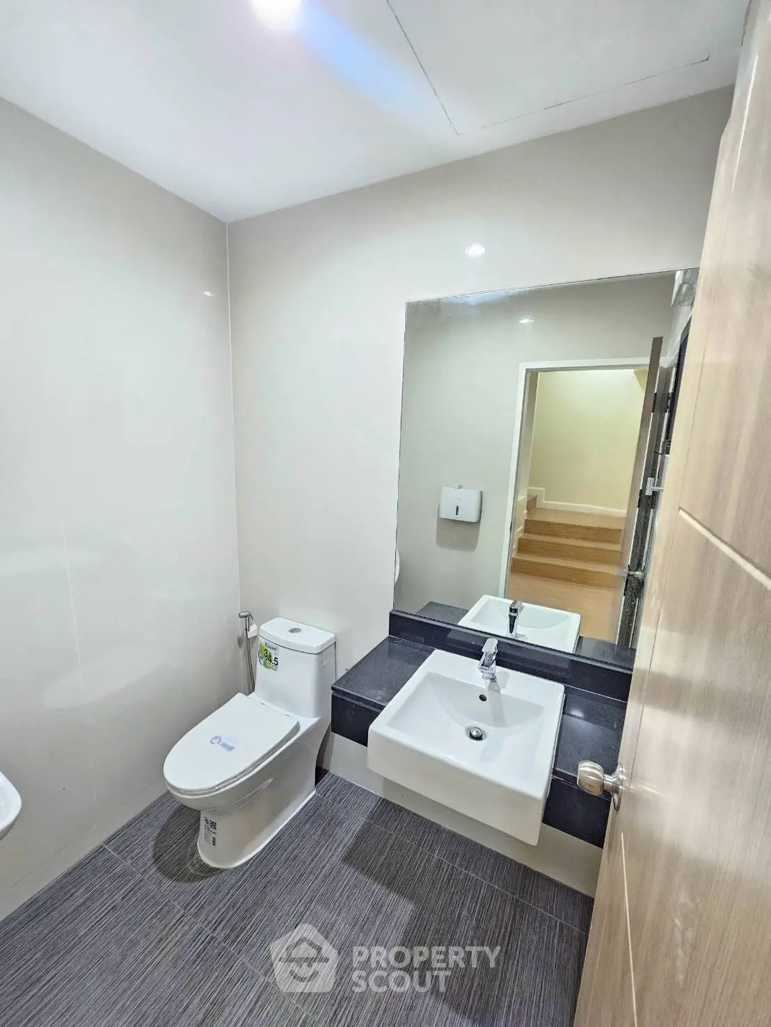 Modern bathroom with sleek fixtures and large mirror in a contemporary home.