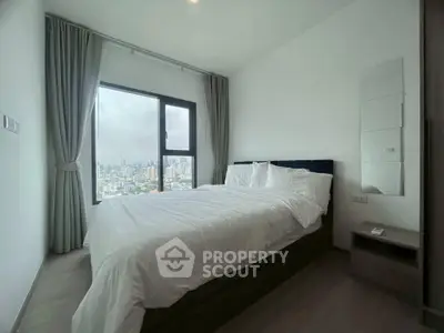 Modern bedroom with city view, featuring a cozy bed and large window with curtains.
