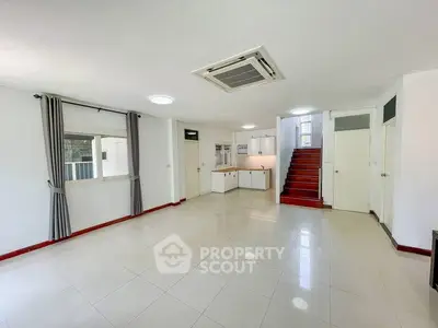 Spacious open-plan living area with modern kitchen and staircase, perfect for family gatherings.
