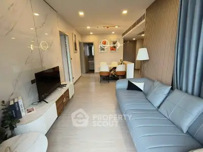 Modern living room with sleek furniture and open layout, featuring a stylish sofa and dining area.