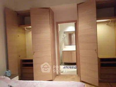 Spacious bedroom with open closets and view into modern bathroom