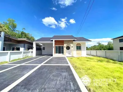 Modern single-story house with spacious driveway and lush green lawn under clear blue sky.