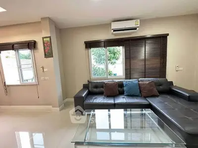 Modern living room with sleek black sofa and large windows, featuring air conditioning and stylish decor.